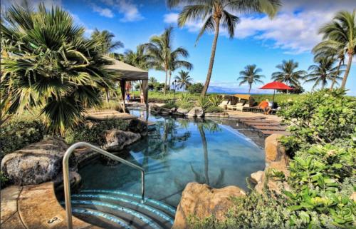 a pool with a waterfall and palm trees at 2 Bedroom OCEAN VIEW LUXURY resort condo with extra large balcony in Lahaina