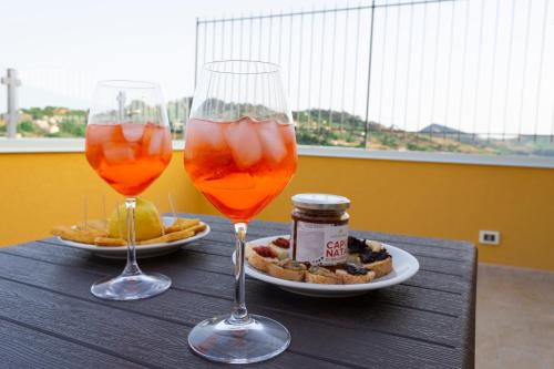 two wine glasses sitting on a table with a plate of food at La Dimora Di Segesta B&B in Calatafimi
