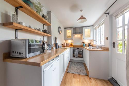 une cuisine avec des placards blancs et un comptoir avec un four micro-ondes dans l'établissement Charlie's Cottage, à Ludlow