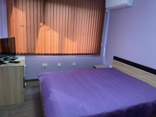 a bedroom with a purple bed and a window at Къща за гости Станеви in Ribarica