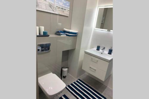 a bathroom with a white toilet and a sink at Przytulny apartament do wynajęcia in Reda