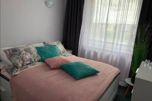 a bedroom with a bed with pillows and a window at Przytulny apartament do wynajęcia in Reda