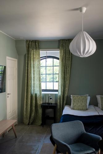 a bedroom with a bed and a window and a chair at Rörums Gårdshotell in Simrishamn