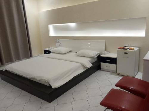 a bedroom with a bed and a red chair at Corniche Palace Hotel in Ajman 