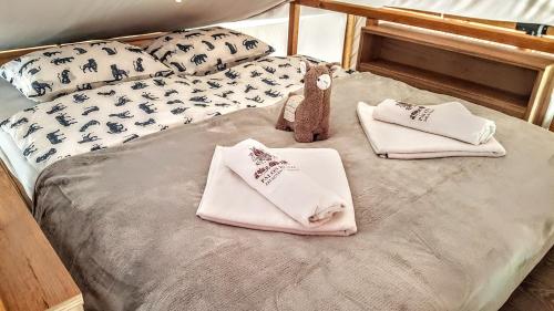 a bed with towels and pillows on it at Pálos Resort in Zalacsány