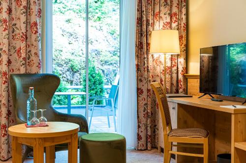 een hotelkamer met een bureau, een televisie en een tafel bij Robenstein Aktivhotel & SPA in Zwiesel