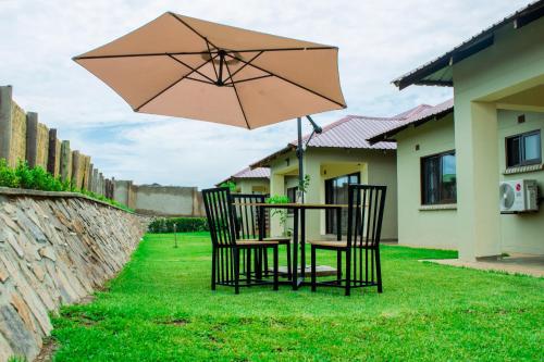 a table and chairs with an umbrella in the yard at Douglas Lodge & Apartments in Lilongwe