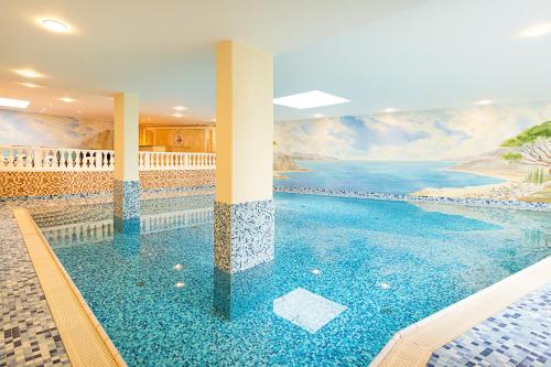 a pool in a house with a painting on the wall at Robenstein Aktivhotel & SPA in Zwiesel