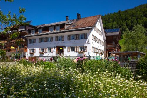 une maison dans les montagnes avec un champ de fleurs dans l'établissement Sonne Bezau - Familotel Bregenzerwald, à Bezau