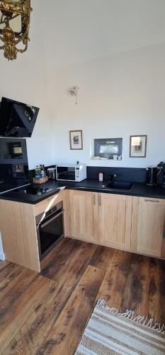 a kitchen with wooden cabinets and a black counter top at Le Pigeonnier Spa du Panty Gîte rural de charme in Saint-Tricat