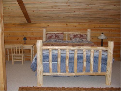 Dormitorio en cabaña de madera con cama y mesa en Comanche Lodge, en Custer