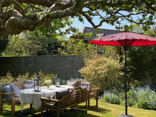 a table with a red umbrella in a garden at Saddlers B&B in Funtington