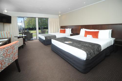 a hotel room with two beds and a balcony at Quality Hotel Lincoln Green in Auckland