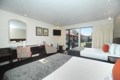 a hotel room with two beds and a desk at Quality Hotel Lincoln Green in Auckland