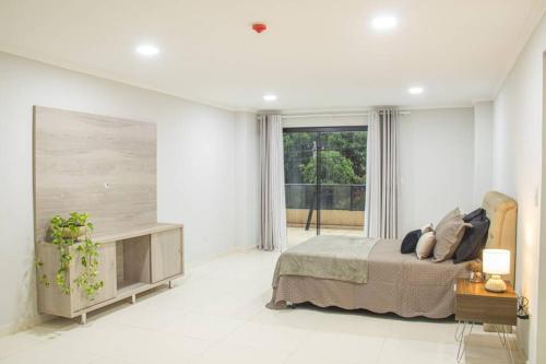 a white bedroom with a bed and a large window at Apartamento cómodo y bien localizado en CDE in Ciudad del Este
