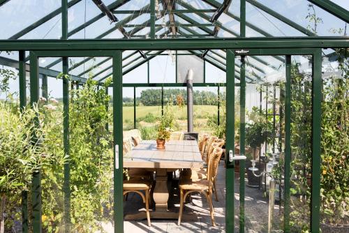 a glass greenhouse with a table and chairs in it at Rörums Gårdshotell in Simrishamn