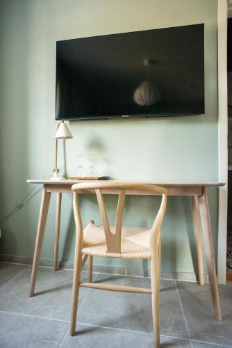 a desk with a chair and a television on a wall at Rörums Gårdshotell in Simrishamn