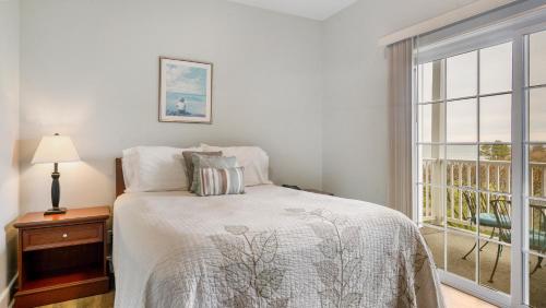 a white bedroom with a bed and a window at The Cliffside Resort Condominiums in Greenport