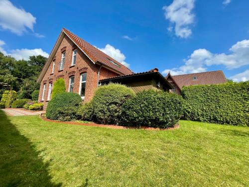 een stenen huis met struiken voor een tuin bij Ferienhaus an der Seefahrtschule in Großefehn 