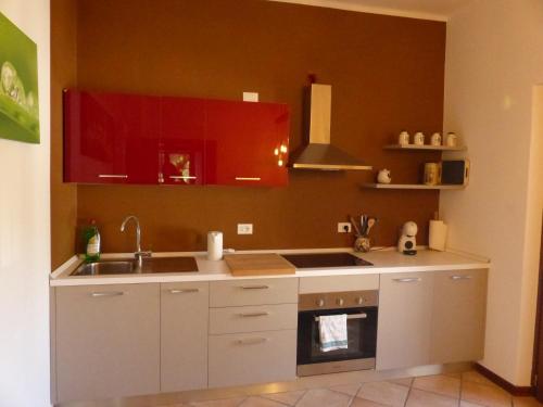 een keuken met rode kasten, een wastafel en een oven bij Appartamento Trentino I in Comano
