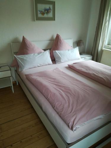 a large bed with pink sheets and pillows at Haus Toni in Bad Füssing