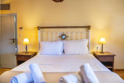 a bedroom with a large white bed with two lamps at Trapela Areopolis, Boutique Hotel in Areopolis
