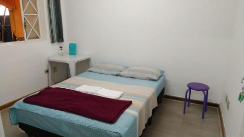um pequeno quarto com uma cama e um banco roxo em Casa Paulista em São Paulo