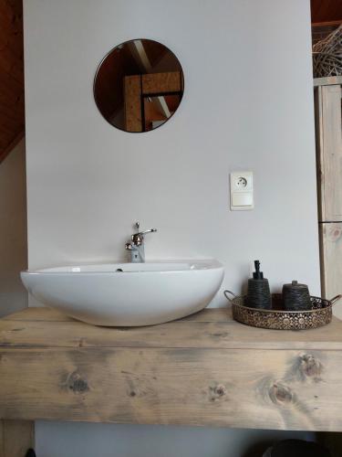 een badkamer met een witte wastafel en een spiegel bij La Marilon in Veurne