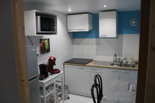 une petite cuisine avec des armoires blanches et un évier dans l'établissement les lauriers de Joelle, à Peyrolles-en-Provence