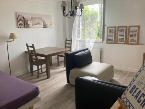 a living room with a table and a chair and a couch at Appartement 2/3 personnes à 10 minutes de Contis plage (Saint Julien en Born) in Saint-Julien-en-Born