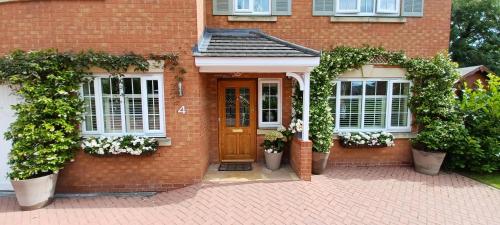 a brick house with a wooden door and two windows at Harlequin B&B Ledbury in Ledbury