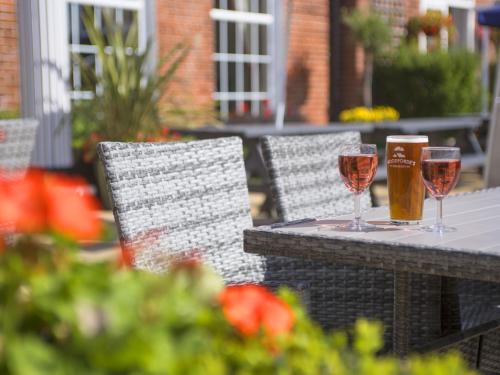two glasses of wine on a table with chairs at The Old Hall Hotel in Caister-on-Sea