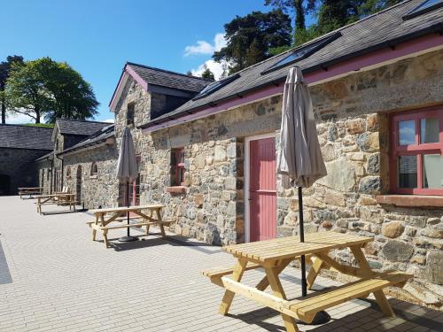 a couple of picnic tables with an umbrella in front of a building at Cobbles cottage - 2 bedroom stone built cottage in Ballynahinch