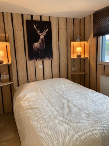 um quarto com uma cama com uma fotografia de um veado na parede em Chalet des Campanules avec Sauna em Vielsalm