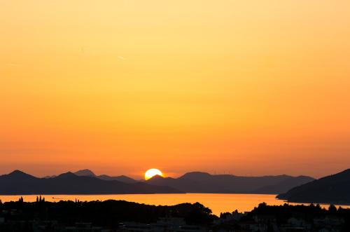 a sunset over the water with a city and mountains at Apartment Marlo in Dubrovnik