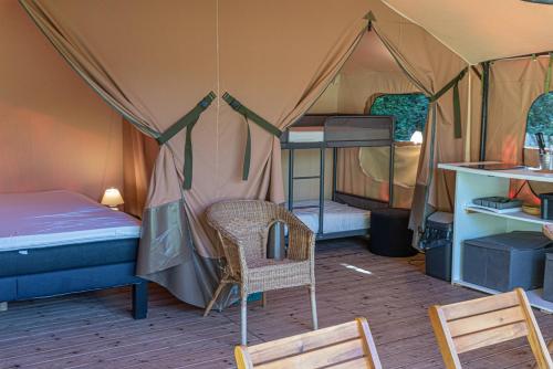 Cette chambre comprend une tente avec un lit et une chaise. dans l'établissement Camping Naéco Audierne, à Plouhinec