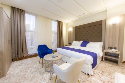 una habitación de hotel con una cama grande y sillas en جولدن دلة للشقق المخدومة en Buraidah