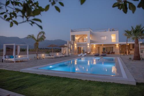 uma casa grande com uma piscina em frente em Villa Pnoe Seaside em Kalamaki