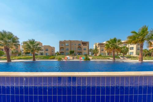 ein großer Pool mit Palmen und Gebäuden in der Unterkunft Golden Apartments El Gouna in Hurghada