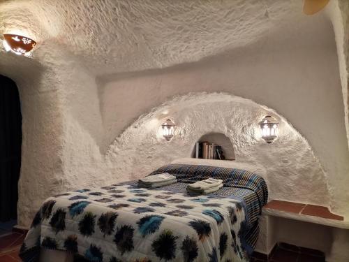 a white room with a bed in a stone wall at Casa Cueva Guadix in Guadix