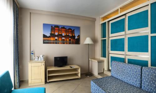 a living room with a couch and a tv in a room at Ephesia Holiday Beach Club in Kusadası