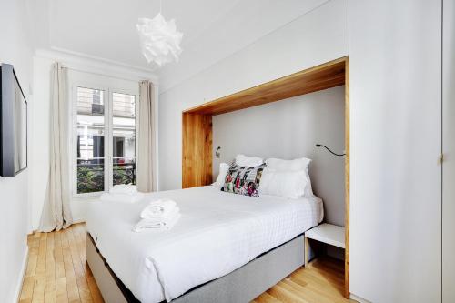 une chambre blanche avec un grand lit et une fenêtre dans l'établissement Pick A Flat's Apartment in Marais/Oberkampf - bvd du Temple, à Paris