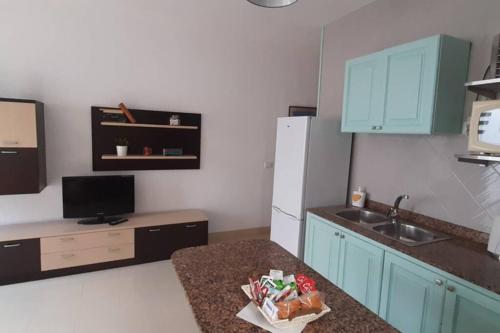 cocina con armarios azules, fregadero y encimera en Los Nudos, acogedor apartamento con patio privado., en Agaete