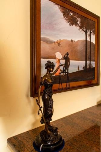 a bronze statue next to a painting on a wall at Hotel Wollner in Sopron