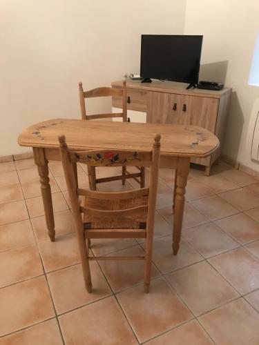 une table en bois avec une chaise et une télévision dans l'établissement le studio, à Sarlat-la-Canéda