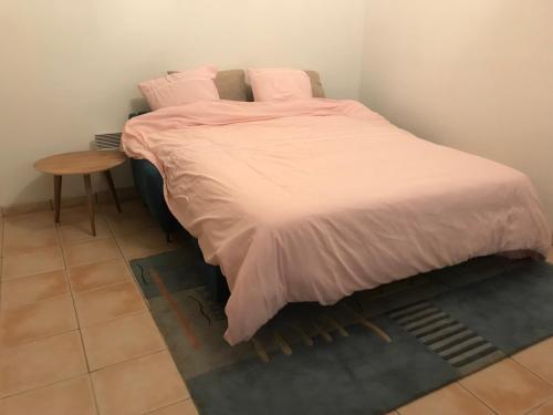 - un lit avec des draps roses et une table dans une chambre dans l'établissement le studio, à Sarlat-la-Canéda