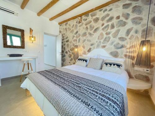 una camera con un grande letto e un muro di pietra di Deco Suites a Naxos Chora