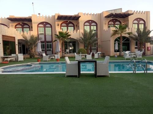 a resort with a pool and chairs and a building at Corniche Palace Hotel in Ajman 
