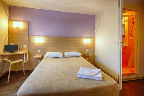 a bedroom with a large bed and a desk and a television at Hôtel Formules Club in Cenon