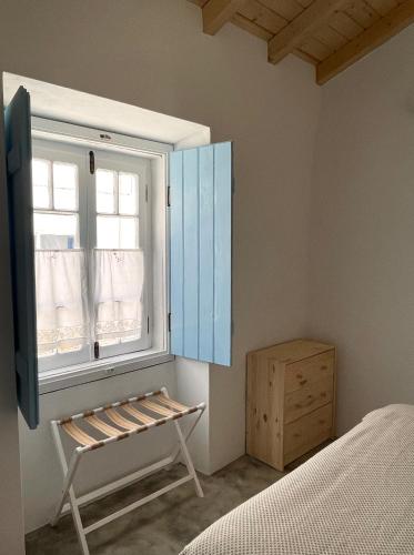 a bedroom with a window and a bench next to a bed at São Vicente in Vila Nova de Milfontes